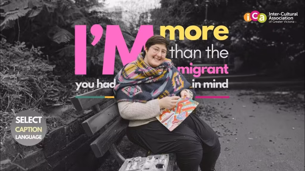 A person smiles while sitting on a bench holding a colourful booklet. Text reads, "I'm more than the immigrant you had in mind."