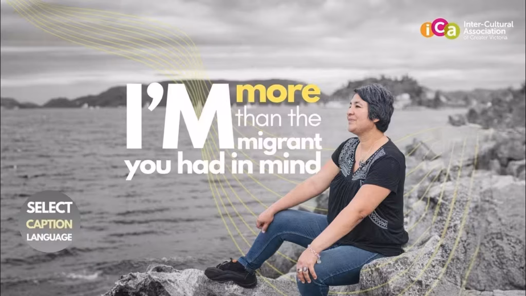 A woman sits on rocks by the water, looking to the right. Text reads "I'm more than the immigrant you had in mind.