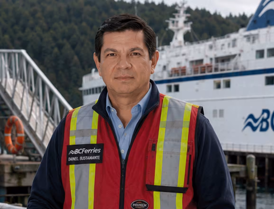 Daniel Bustamante in a BC Ferries uniform with a large white ferry behind him.
