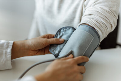 Doctor's hands place a blood pressure cuff on a patient's arm during a medical check-up.