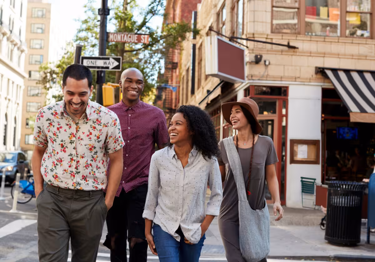 Four Casually Dressed Friends Walking Together City Street Four casually dressed friends are walking together on a city street, smiling and laughing.